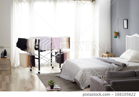 Laundry drying rack,  white pillow on bed 108105622