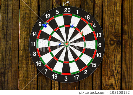 darts hanging on a wooden wall with a dart stuck in the center 108108122