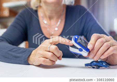 Woman is inserting finger into electronic pulse oximeter. Woman is inserting finger into electronic pulse oximeter. 108110060