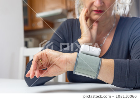 Woman is sadly looking at result of blood pressure measurement Woman is sadly looking at result of blood pressure measurement 108110066