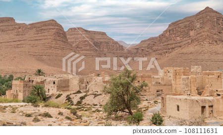 Traditional Moroccan clay houses with flat roofs, high clay walls and small windows in the Atlas mountain gorge by Ziz river, Morocco 108111631