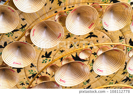 Many similar traditional Vietnamese conical hats attached to the ceiling for decoration a holiday Many similar traditional Vietnamese conical hats attached to the ceiling for decoration a holiday 108112778