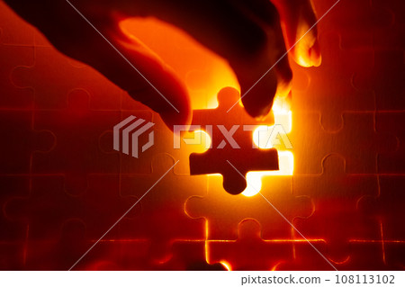 Pieces of a jigsaw puzzle filled with orange lights by hand Success concept Pieces of a jigsaw puzzle filled with orange lights by hand Success concept 108113102