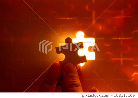 Pieces of a jigsaw puzzle filled with orange lights by hand Success concept Pieces of a jigsaw puzzle filled with orange lights by hand Success concept 108113109