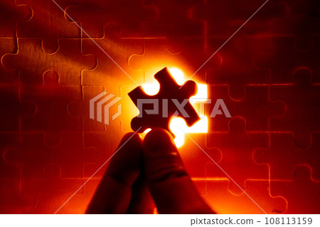 Pieces of a jigsaw puzzle filled with orange lights by hand Success concept Pieces of a jigsaw puzzle filled with orange lights by hand Success concept 108113159