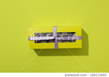 Chocolate candies in box with ribbon on green background, top view 108113684