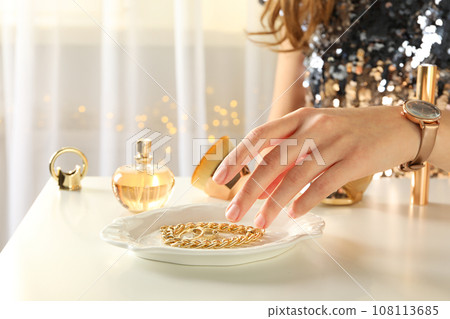 A bottle of perfume on a table with gold ornaments A bottle of perfume on a table with gold ornaments 108113685