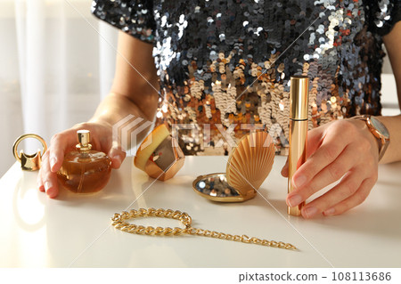 A bottle of perfume on a table with gold ornaments A bottle of perfume on a table with gold ornaments 108113686