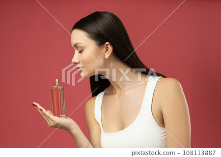 An attractive young girl with perfume in her hand 108113887