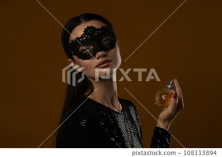 Attractive girl in a mask with perfume in her hand Attractive girl in a mask with perfume in her hand 108113894