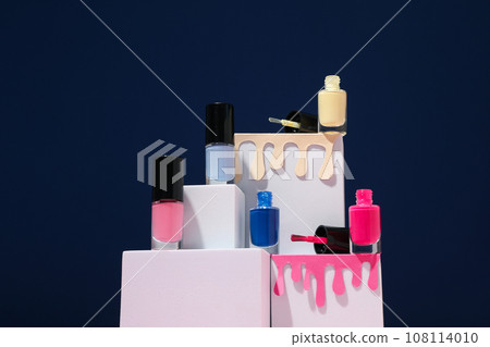 Multicolored nail polishes with white cubes on a dark background 108114010