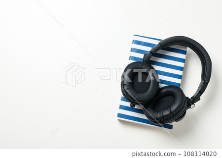 Headphones on book on white background, space for text Headphones on book on white background, space for text 108114020