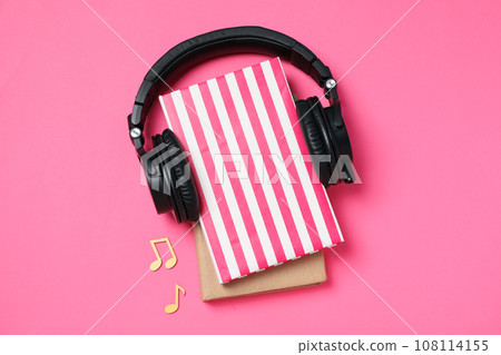 Headphones on books on pink background, top view 108114155