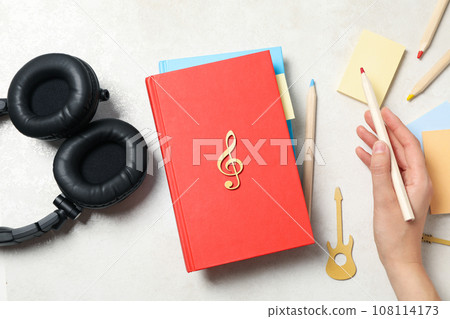 Headphones, books, pencils and female hand on light background, top view Headphones, books, pencils and female hand on light background, top view 108114173