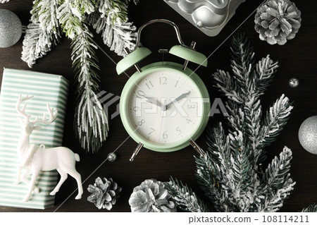 A clock with a New Year's decoration, on a dark background. 108114211