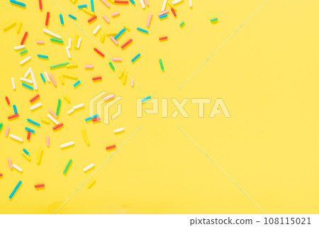 flat lay colorful sprinkles over yellow background 108115021