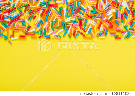 flat lay colorful sprinkles over yellow background 108115023
