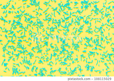 flat lay of blue sprinkles over yellow background 108115029