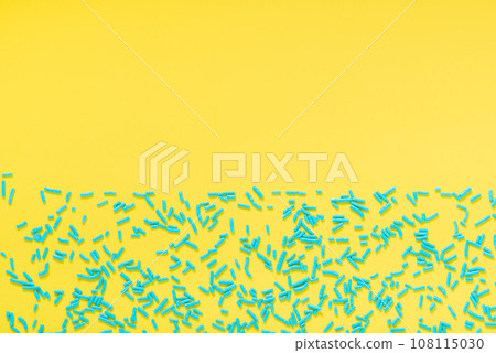 flat lay of blue sprinkles over yellow background 108115030