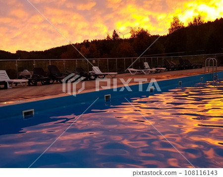 Swimming pool with sun loungers at sunset Swimming pool with sun loungers at sunset 108116143