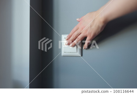 Female hand pressing light switch in apartment closeup 108116644