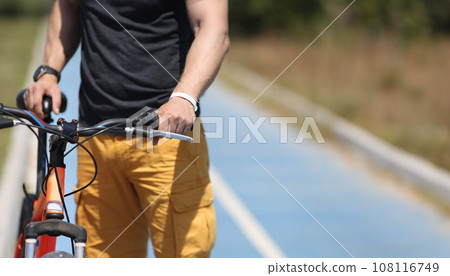 Man with mountain bike standing on bicycle path closeup Man with mountain bike standing on bicycle path closeup 108116749