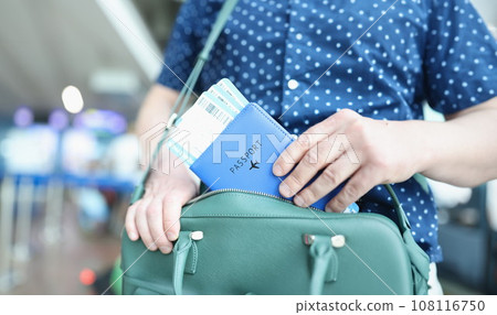 Man putting passport with plane tickets in laptop bag closeup Man putting passport with plane tickets in laptop bag closeup 108116750
