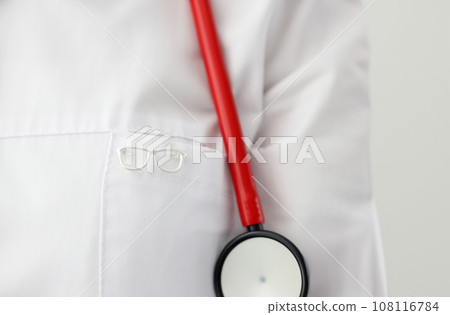 Eyeglass shape icon hanging on ophthalmologist gown closeup Eyeglass shape icon hanging on ophthalmologist gown closeup 108116784