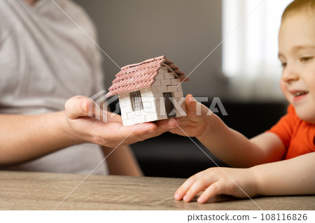 A father gives his son a small house. The concept of transfer of property and inheritance. Real estate. housing as a gift, apartment or house A father gives his son a small house. The concept of transfer of property and inheritance. Real estate. housing as a gift, apartment or house 108116826