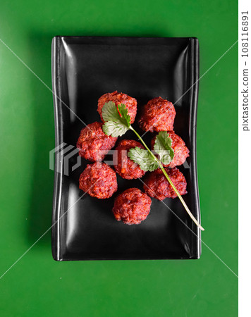 beef and pork meatballs with parsley on a black plate, on a green background. View from above. Chinese cuisine beef and pork meatballs with parsley on a black plate, on a green background. View from above. Chinese cuisine 108116891