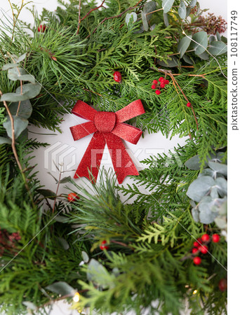 Stylish Christmas wreath for the interior. Handmade wreath with a beautiful red bow. Celebration atmosphere. 108117749