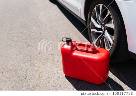 A red plastic can is in the middle of the road next to a white car. Refueling problems. 108117758