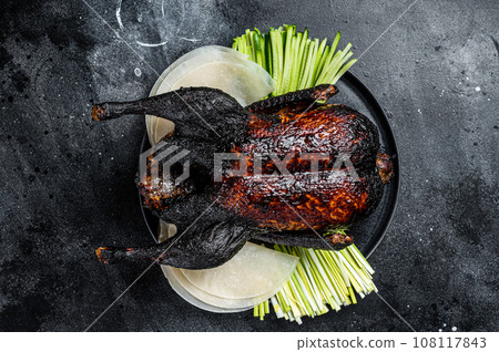 Traditional whole roasted Christmas Peking duck with herbs and sauce. Black background. Top view 108117843