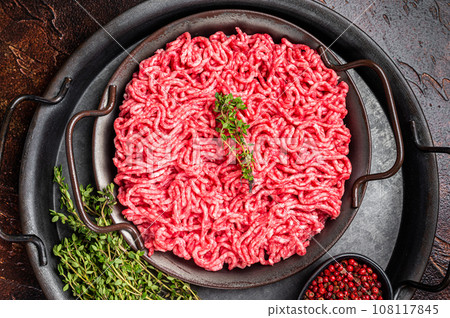 Raw Mince, minced Ground beef meat in a kitchen tray. Dark background. Top view Raw Mince, minced Ground beef meat in a kitchen tray. Dark background. Top view 108117845