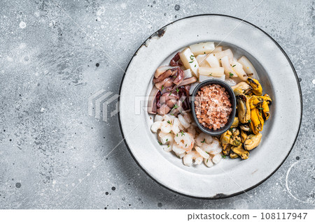 Raw seafood mix in a rustic plate. Gray background. Top view. Copy space 108117947