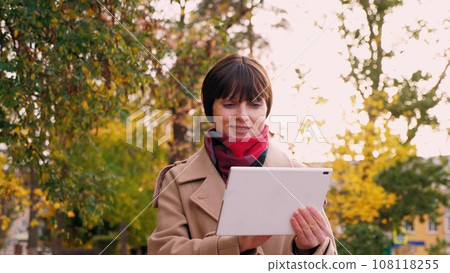 Woman prepares presentation on tablet for meeting with investor in park 108118255