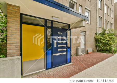 a blue and yellow door on the side of a brick building in an urban area with trees, bushes and plants a blue and yellow door on the side of a brick building in an urban area with trees, bushes and plants 108118700