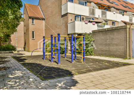 an outdoor play area in front of a brick building with blue and yellow playground equipment on the ground next to it an outdoor play area in front of a brick building with blue and yellow playground equipment on the ground next to it 108118744