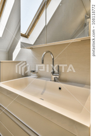 a bathroom with a skylight above it and a sink in the fore - image is taken from an angle 108118772