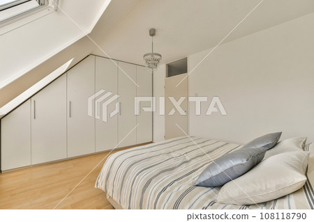 a bedroom with a bed and cupboards on the wall in front of the bed is an attic style loft 108118790