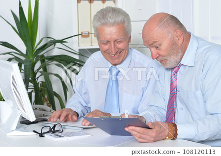 Two old business men sitting at desk and working Two old business men sitting at desk and working 108120113