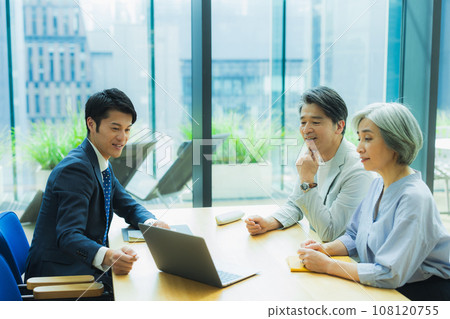 A man in a suit explaining to a middle-aged couple 108120755