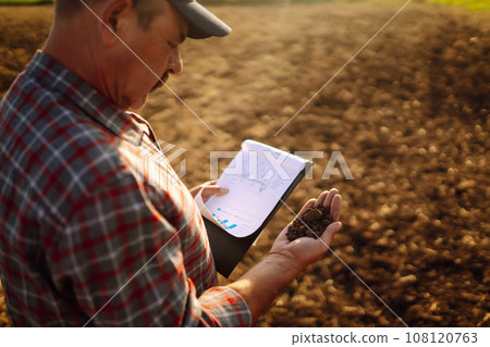 Farmer is checking soil quality before sowing. Agriculture, gardening or ecology concept. Farmer is checking soil quality before sowing. Agriculture, gardening or ecology concept. 108120763
