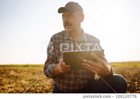 Male hands touching soil on the field. Expert hand of farmer checking soil health. Ecology concept. Male hands touching soil on the field. Expert hand of farmer checking soil health. Ecology concept. 108120776