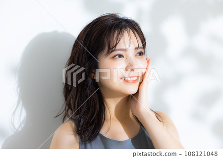 A woman in the sunlight filtering through the trees 108121048