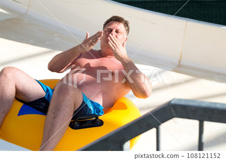 A man riding a water slide blows a kiss A man riding a water slide blows a kiss 108121152