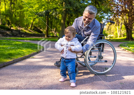 Dad on wheelchair playing with his little son in the park 108121921