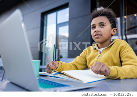 African american schoolboy doing lessons and looking involved African american schoolboy doing lessons and looking involved 108123283