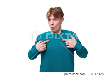 young surprised guy with short red hair dressed in a blue pullover on a white background young surprised guy with short red hair dressed in a blue pullover on a white background 108123289