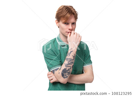 young smart red-haired man dressed in a green t-shirt on a background with copy space. lifestyle young smart red-haired man dressed in a green t-shirt on a background with copy space. lifestyle 108123295